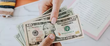 photo of hands exchanging American paper money | payday lending | Tycko & Zavareei LLP