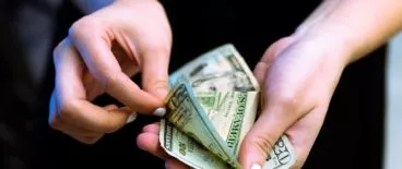 person holding and counting paper money