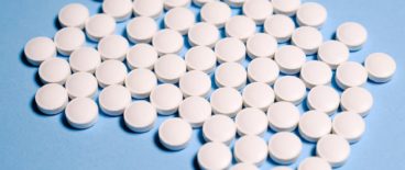 circular, white pills resting on a flat, blue surface