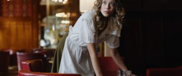 waitress wiping down table while looking up at something out of view