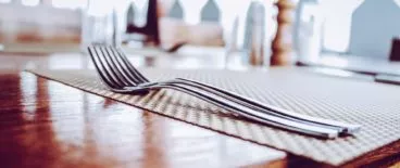 forks resting on napkin on wooden table
