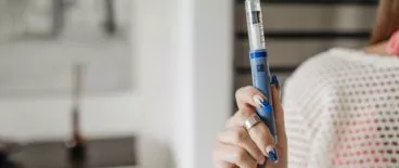 person out of frame holding an insulin pen