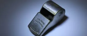 metal whistle resting on flat surface under spotlight